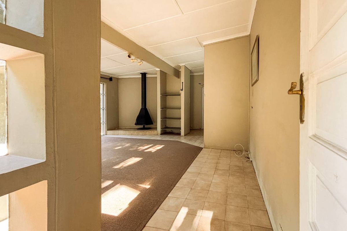 A spacious living area featuring a built-in fireplace, tiled entryway, and carpeted flooring, offering a functional layout with potential for modernization.