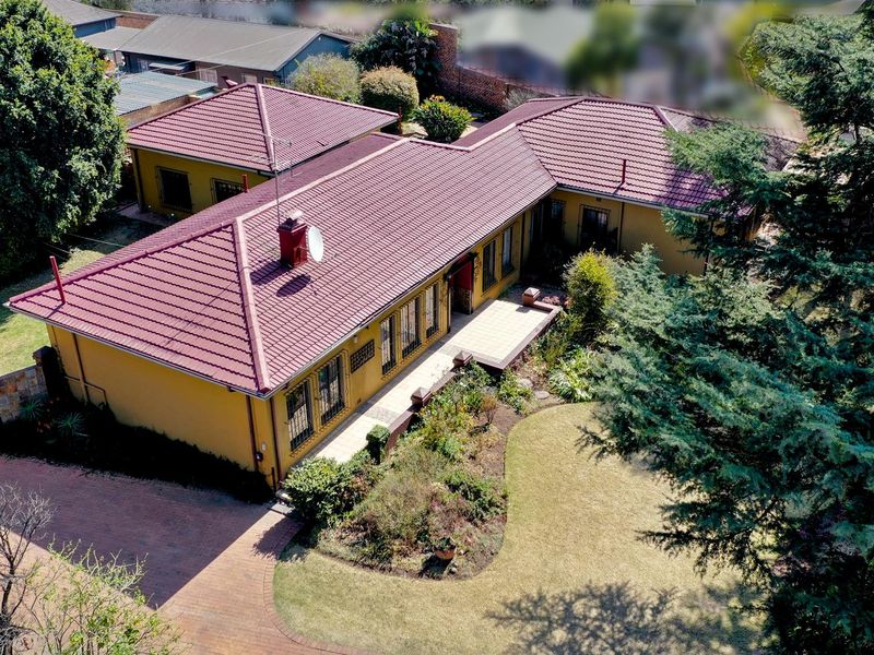 Aerial view of a residential property featuring a tiled roof, brick paved driveway, and established garden surroundings.