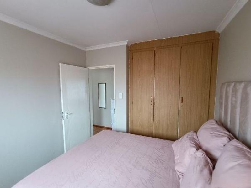 A bedroom featuring built-in wooden cupboards and coving, providing functional storage space within the room.