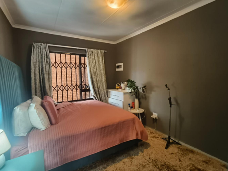 A bedroom featuring dark painted walls, a security gate on the window, and a ceiling light fixture.
