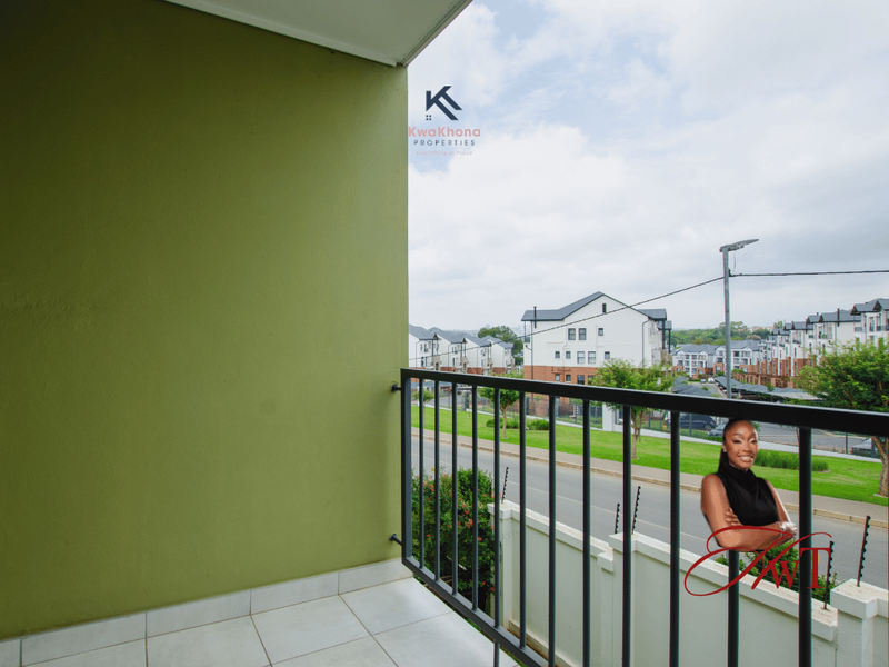 A private balcony featuring tiled flooring and a metal balustrade, offering an elevated view of the surrounding residential complex.