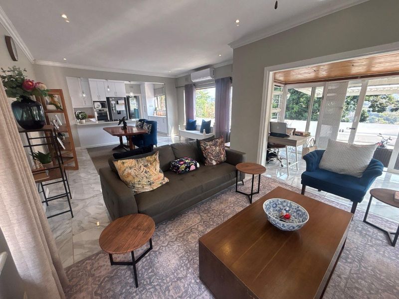 Spacious open-plan living area featuring marble flooring, recessed lighting, and seamless flow to an adjoining sunroom and kitchen with modern cabinetry.
