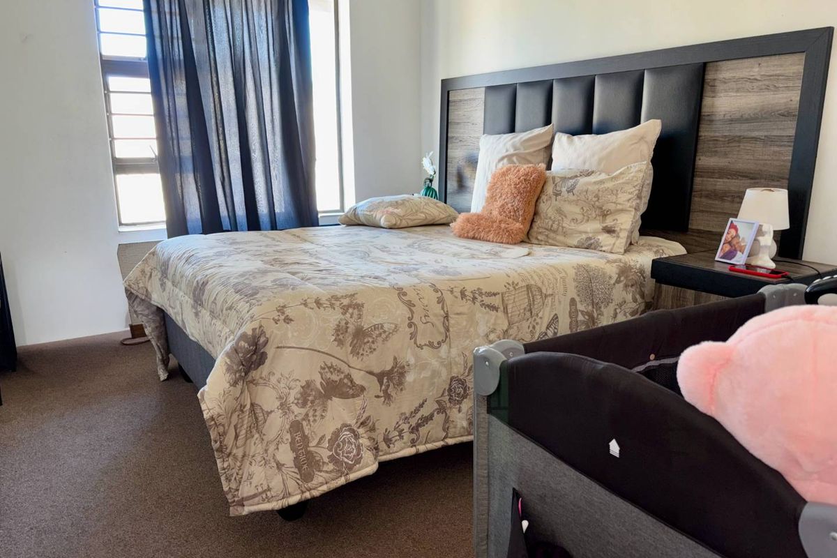 A well-lit bedroom featuring a built-in headboard and carpeted flooring, offering a comfortable and functional living space.