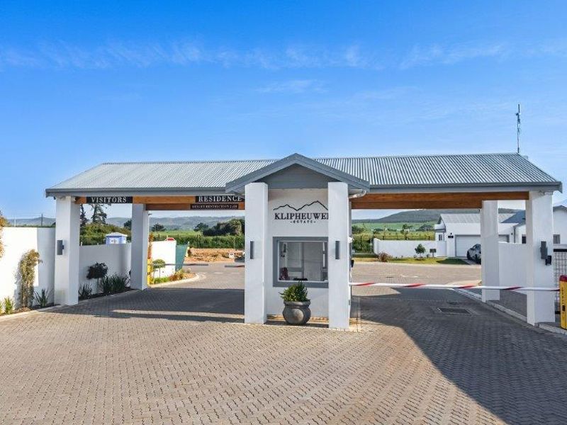 The entrance to Klipheuwe Estate featuring a modern security gatehouse, boom gate access, and paved driveway.