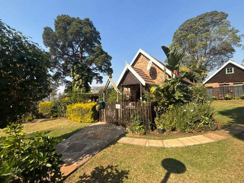 A charming townhouse exterior featuring stone and timber cladding, a paved walkway, and a well-maintained garden entrance.