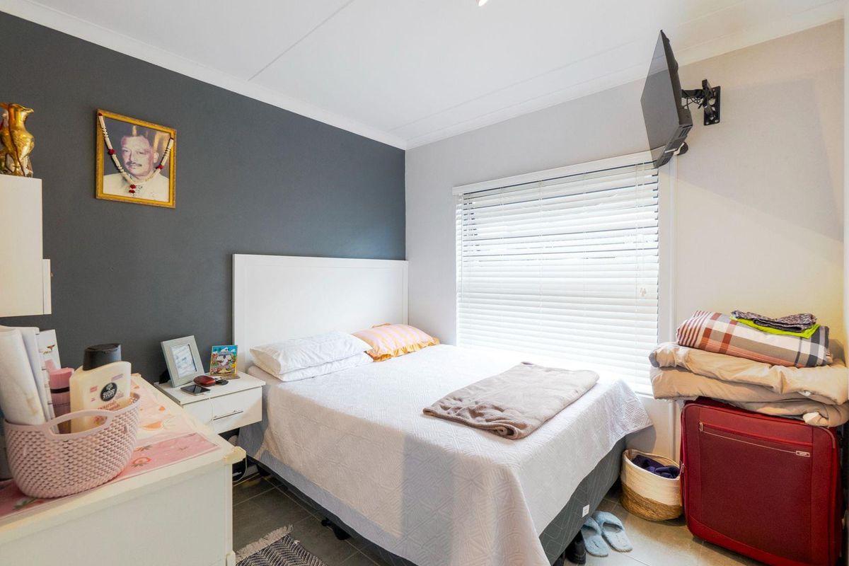 A compact bedroom featuring a dark accent wall, tiled flooring, and a wall-mounted television bracket.