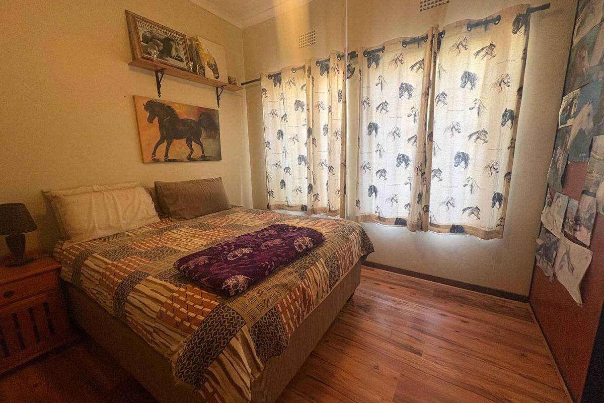 A bedroom featuring laminate flooring, a built-in cupboard, and natural light through large windows.