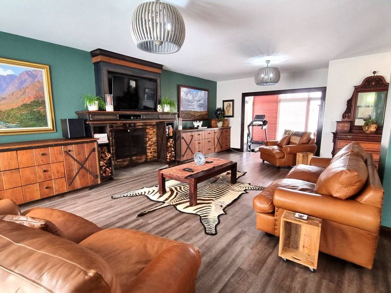 Spacious living room featuring a prominent built-in fireplace, modern laminate flooring, and stylish pendant lighting, creating a warm and inviting atmosphere.
