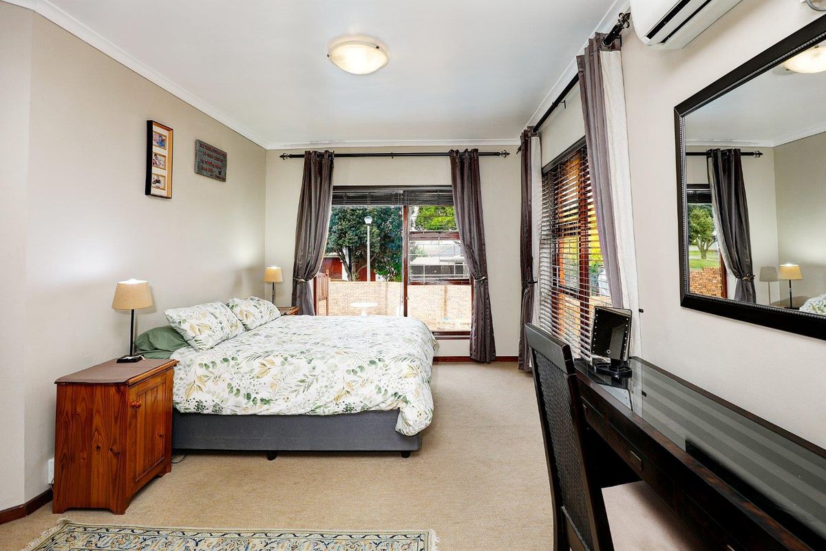 A well-maintained bedroom featuring neutral carpeting, a wall-mounted air conditioning unit, and sliding glass doors providing access to the exterior.