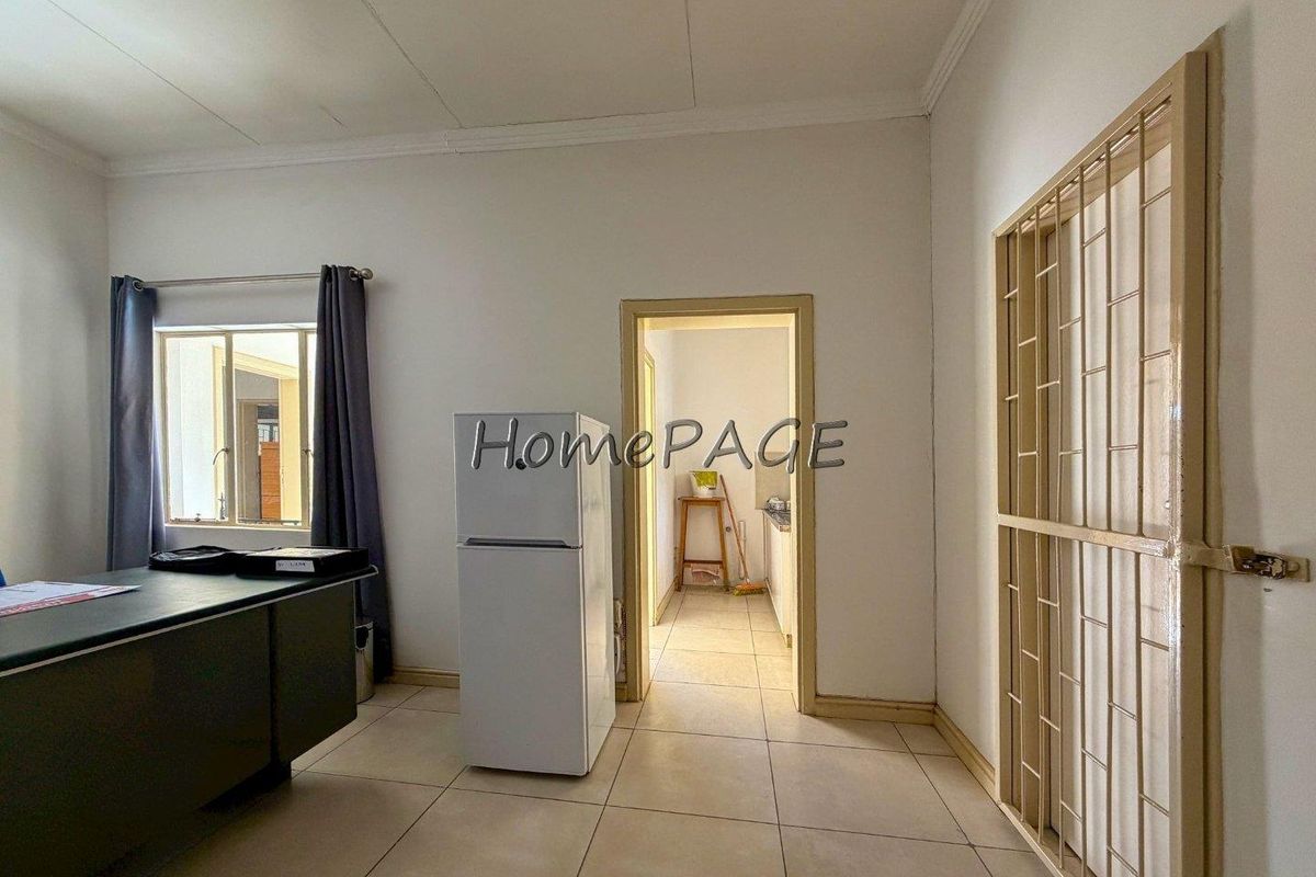 A living area featuring tiled flooring and a security gate, with a doorway leading to an adjacent room.