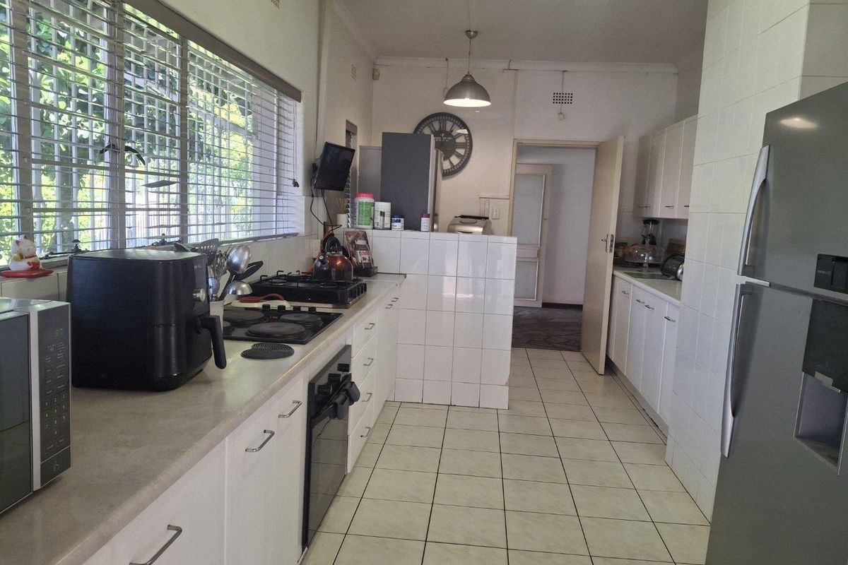 A functional kitchen featuring white cabinetry, tiled flooring, and a combination gas and electric hob, offering a practical layout for daily meal preparation.
