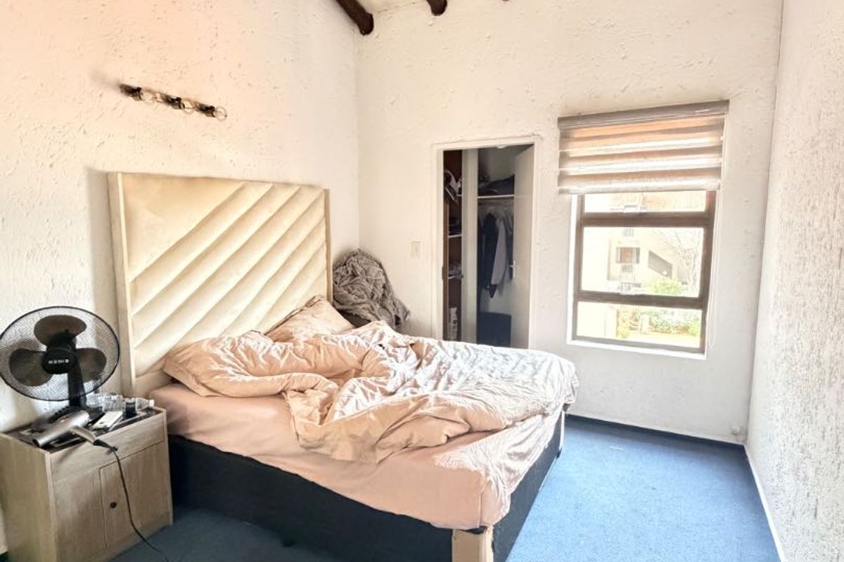 Bedroom featuring high vaulted ceilings with exposed timber beams, a built-in closet, and a window with a roller blind.