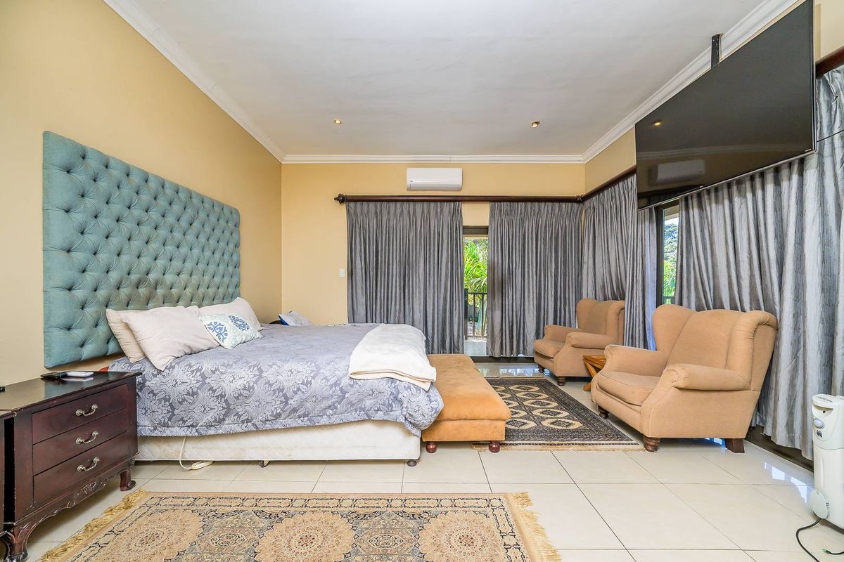 Spacious bedroom featuring tiled flooring, a wall-mounted air conditioning unit, and direct access to an outdoor area through sliding glass doors.