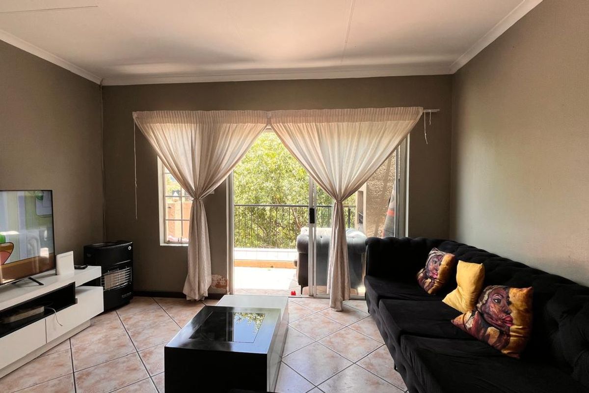 A living room featuring tiled flooring and sliding glass doors that open onto a private balcony, providing natural light and outdoor access.