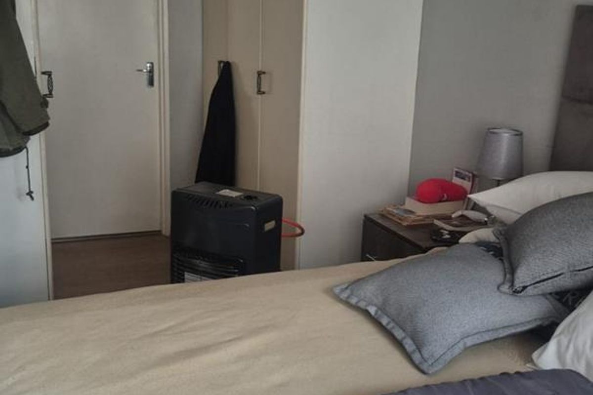 A bedroom featuring built-in cupboards and a ceiling fan, providing functional storage and climate control.