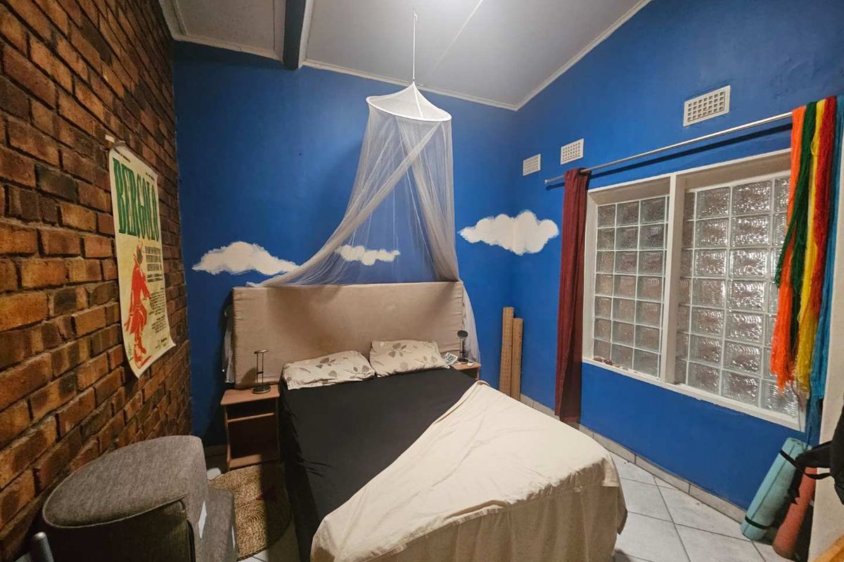 A bedroom featuring a distinctive exposed brick feature wall, tiled flooring, and a glass block window providing natural light.
