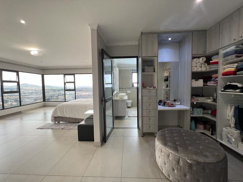 Spacious bedroom featuring built-in cabinetry, a dedicated vanity area, and large windows offering expansive panoramic views, with an adjoining en-suite bathroom.