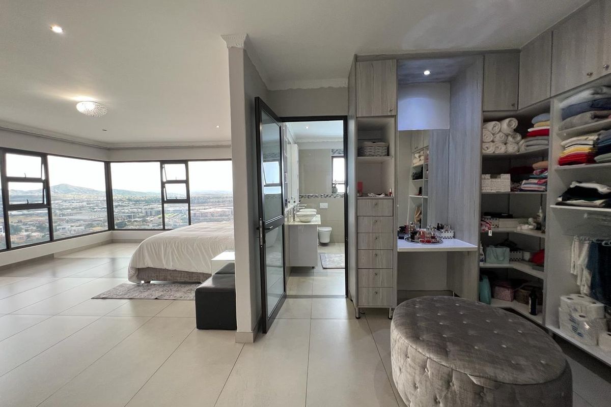 Spacious bedroom featuring built-in cabinetry, a dedicated vanity area, and large windows offering expansive panoramic views, with an adjoining en-suite bathroom.