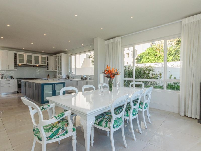 Spacious open-plan kitchen and dining area featuring a large central island, modern cabinetry, tiled floors, and abundant natural light through expansive windows.