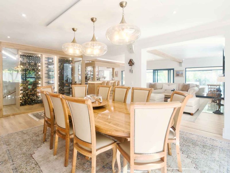 Spacious open-plan dining and living area featuring high-end finishes, recessed lighting, and a sophisticated built-in glass-enclosed wine cellar.