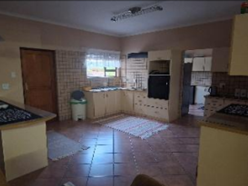 A dated kitchen featuring built-in cabinetry, tiled splashbacks, and tiled flooring, offering a functional layout with potential for modern renovation.