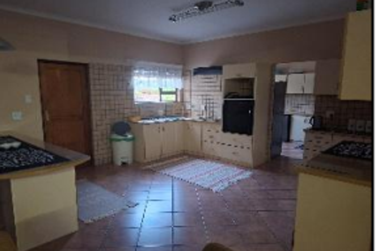 A dated kitchen featuring built-in cabinetry, tiled splashbacks, and tiled flooring, offering a functional layout with potential for modern renovation.