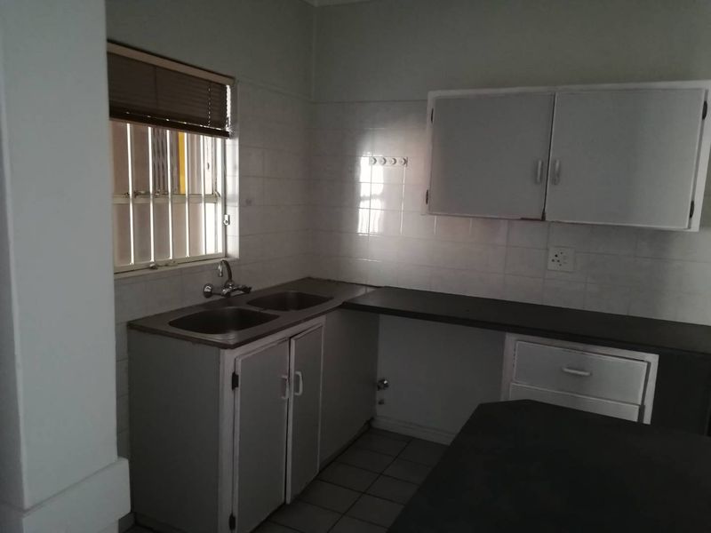 A functional kitchen space featuring built-in cabinetry, double bowl sink, and tiled splashbacks, offering a blank canvas for potential modern updates.