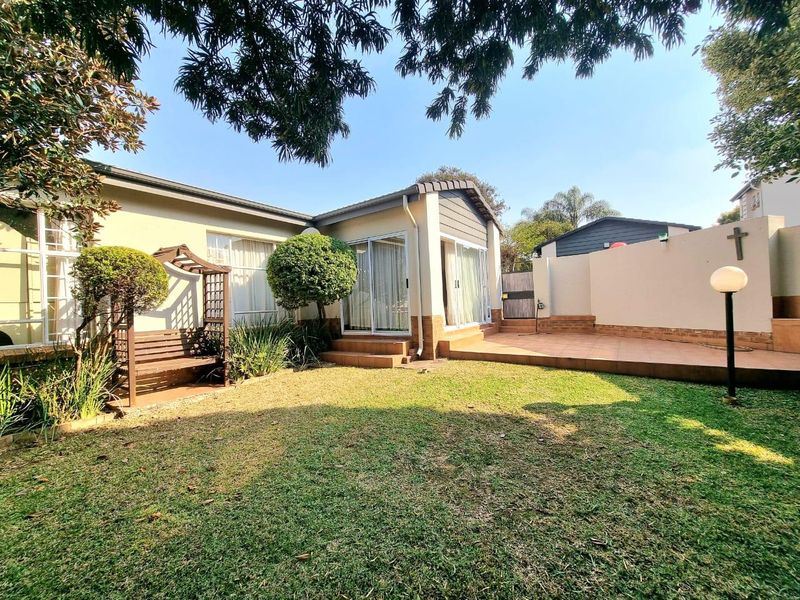 A well-maintained rear garden featuring a tiled patio area, sliding door access to the home, and established landscaping.
