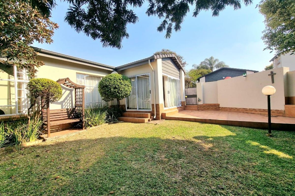 A well-maintained rear garden featuring a tiled patio area, sliding door access to the home, and established landscaping.