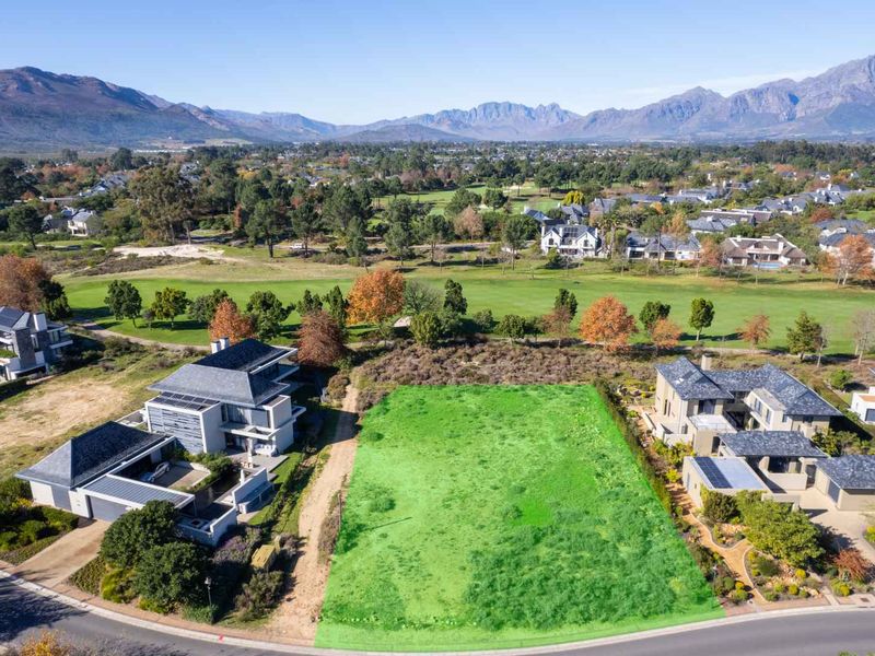 An aerial view of a vacant residential plot situated in a prime location, featuring direct access to a golf course and surrounding established homes.