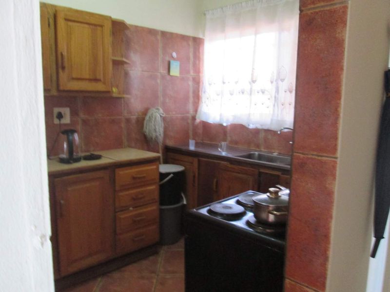 A compact kitchen featuring wooden cabinetry, tiled backsplash, and a built-in electric stove, requiring modernization to improve functionality and aesthetic appeal.