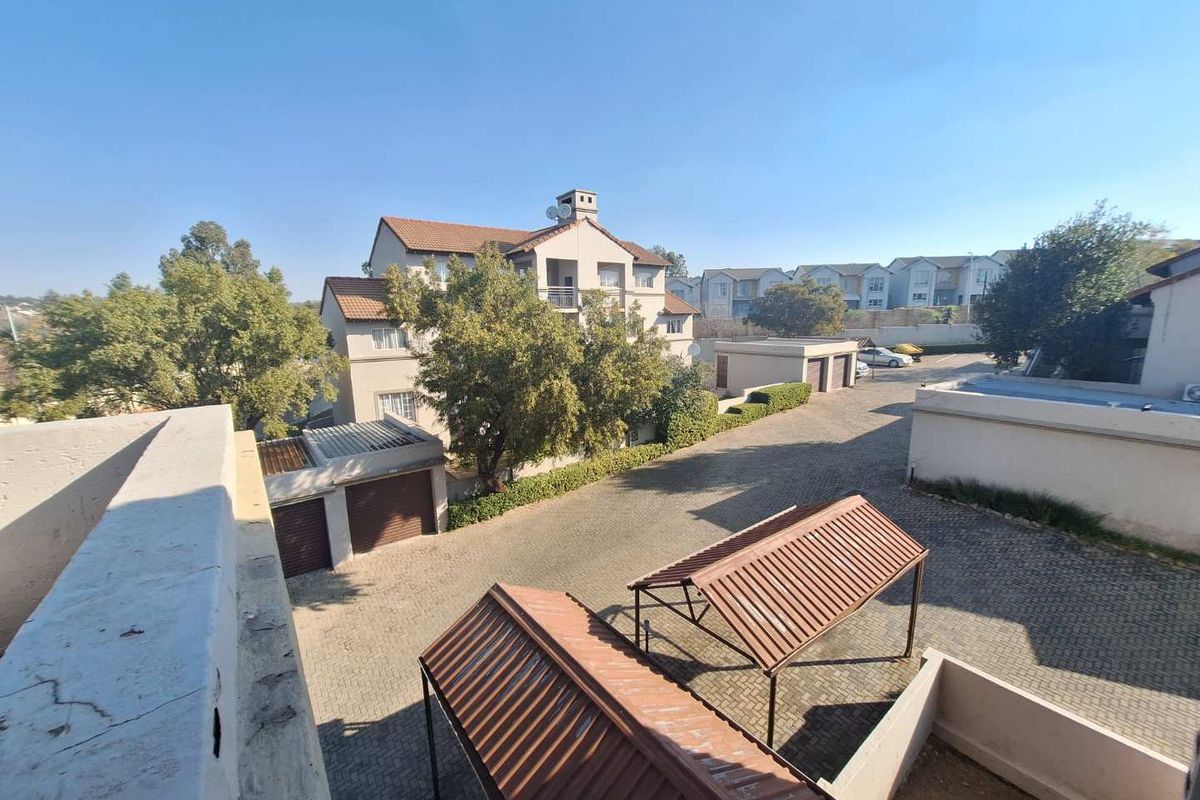 An elevated view of the apartment complex grounds, featuring paved driveways, covered carports, and individual garage units.