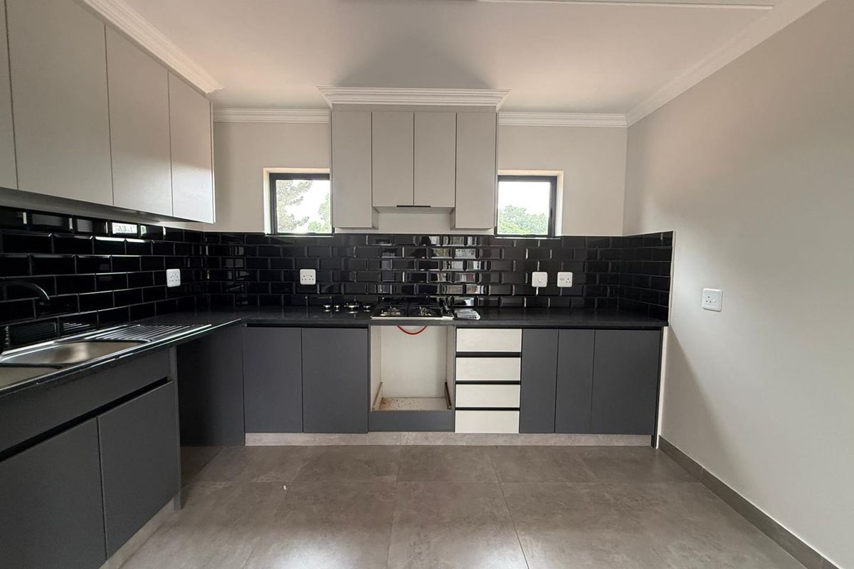 Modern kitchen featuring dark grey cabinetry, contrasting black subway tile backsplash, stone countertops, and integrated gas hob.