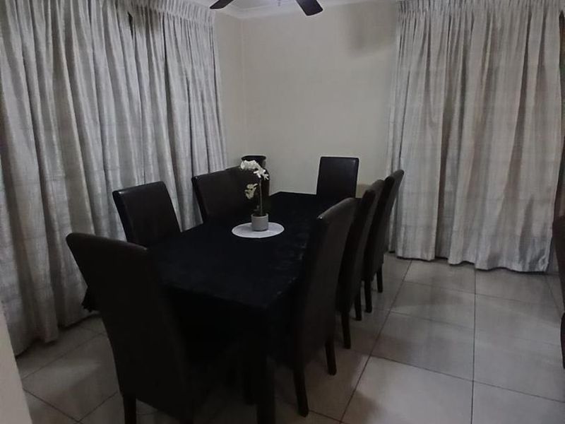 A dining room featuring tiled flooring, a ceiling fan, and floor-to-ceiling curtains.
