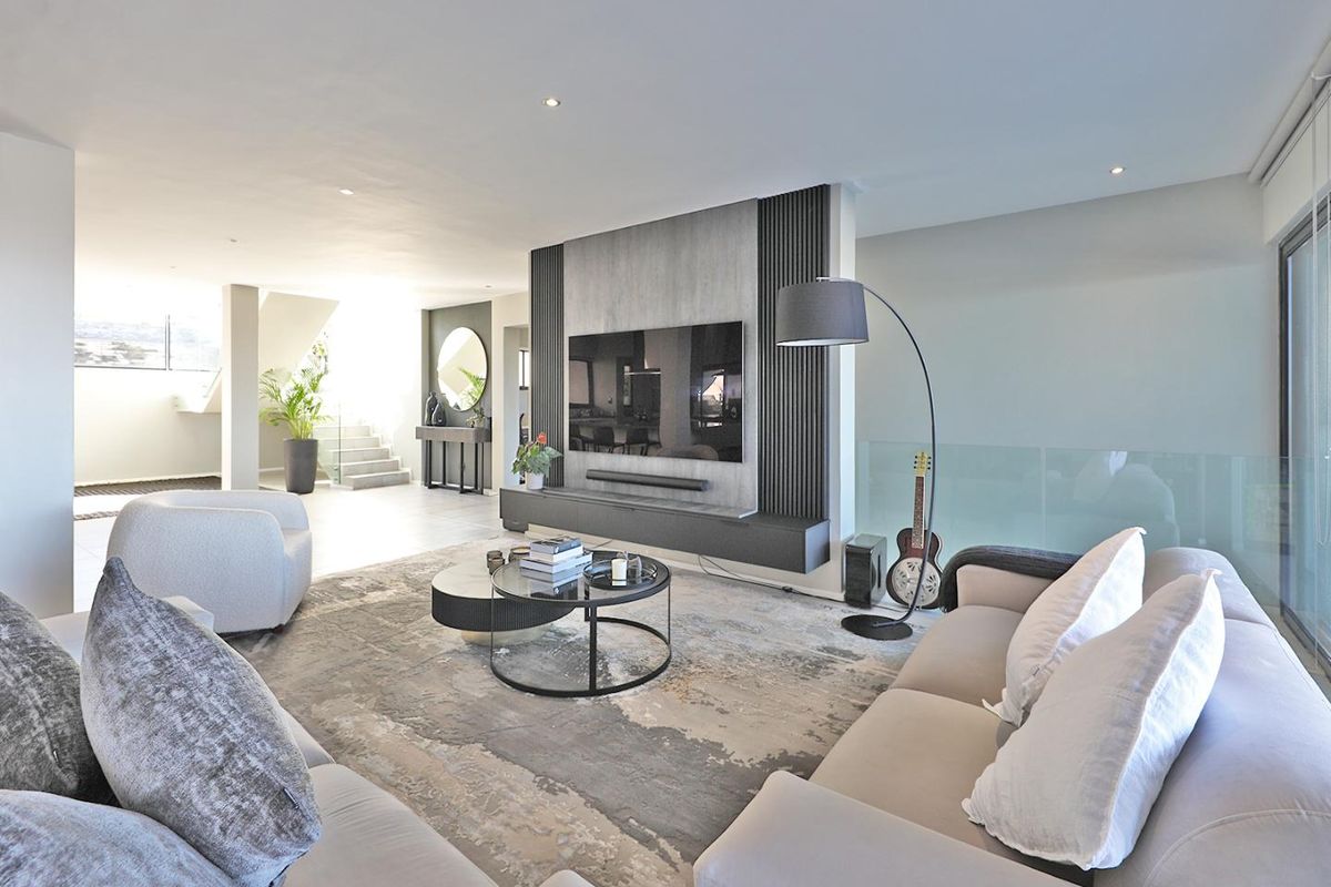 Modern open-plan living area featuring a sleek built-in media wall with integrated cabinetry and recessed lighting, creating a sophisticated and contemporary atmosphere.