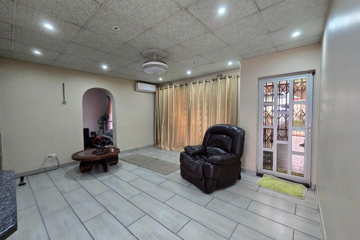 Spacious living area featuring tiled flooring, a drop ceiling with recessed lighting, a split-system air conditioner, and a secure exterior access door.