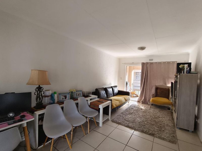 A living room area featuring tiled flooring and a sliding glass door providing access to an outdoor space.