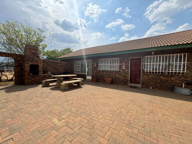 Spacious outdoor patio area featuring a brick built-in braai, paved flooring, and direct access to the home's exterior.