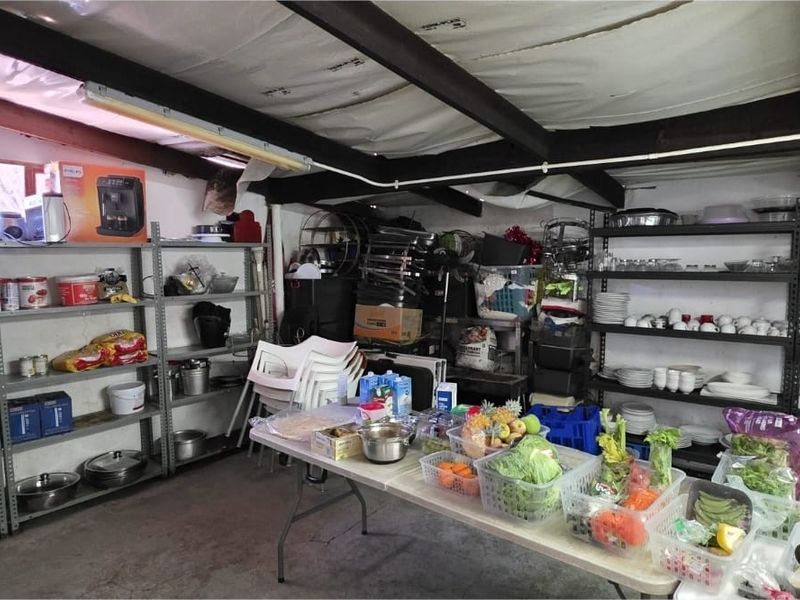 A functional utility or storage space featuring exposed ceiling beams, concrete flooring, and extensive metal shelving units for organized storage.