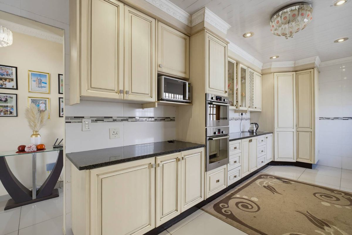 A well-maintained kitchen featuring cream-colored cabinetry, granite countertops, built-in oven and microwave, and elegant crown molding details.