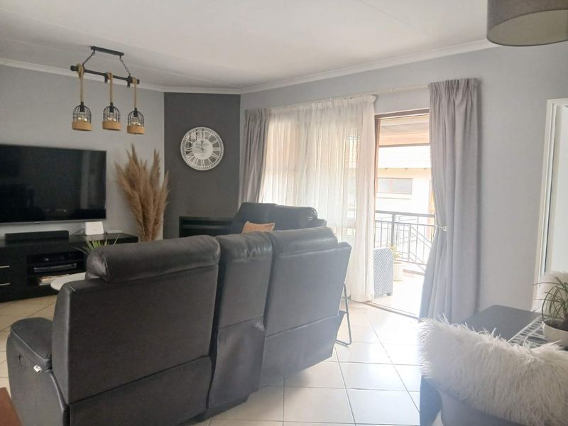 A bright living room featuring tiled flooring, modern pendant lighting, and a sliding glass door providing access to an outdoor balcony area.