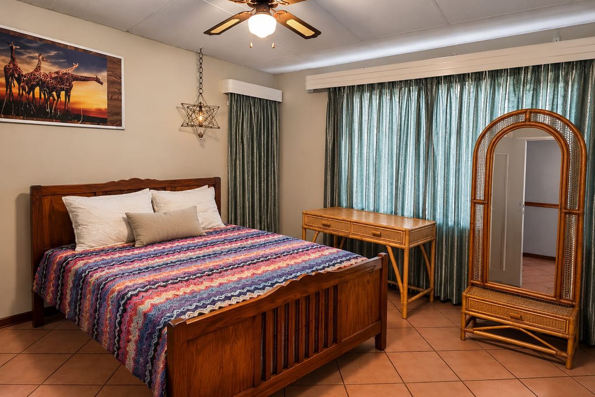 A well-maintained bedroom featuring tiled flooring, a ceiling fan, and large windows with curtain tracks.