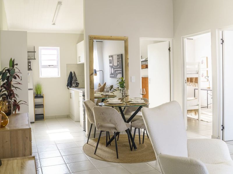 An open-plan living and dining area featuring tiled flooring, neutral walls, and a functional kitchen layout with direct access to adjacent rooms.