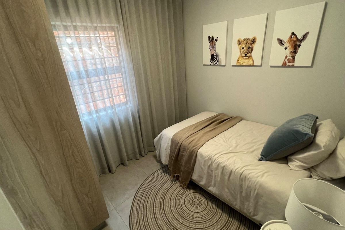 A neat bedroom featuring tiled flooring, a built-in wardrobe, and a window fitted with security bars.