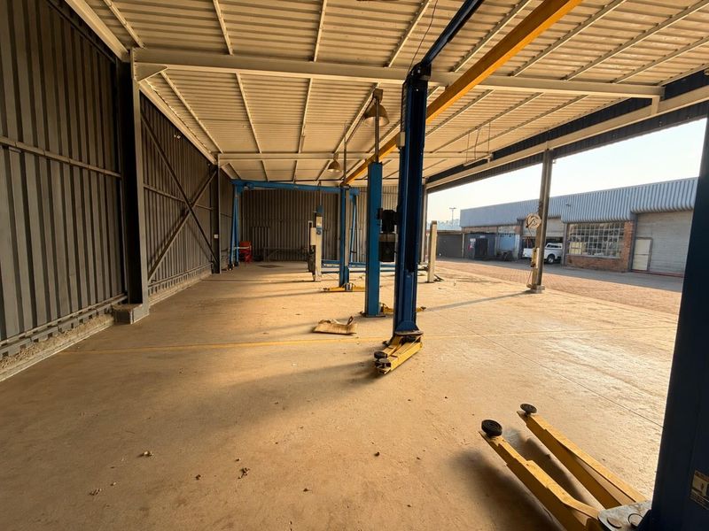Spacious industrial garage facility featuring a steel frame structure, concrete flooring, and multiple built-in vehicle hydraulic lifts, suitable for automotive workshop operations.
