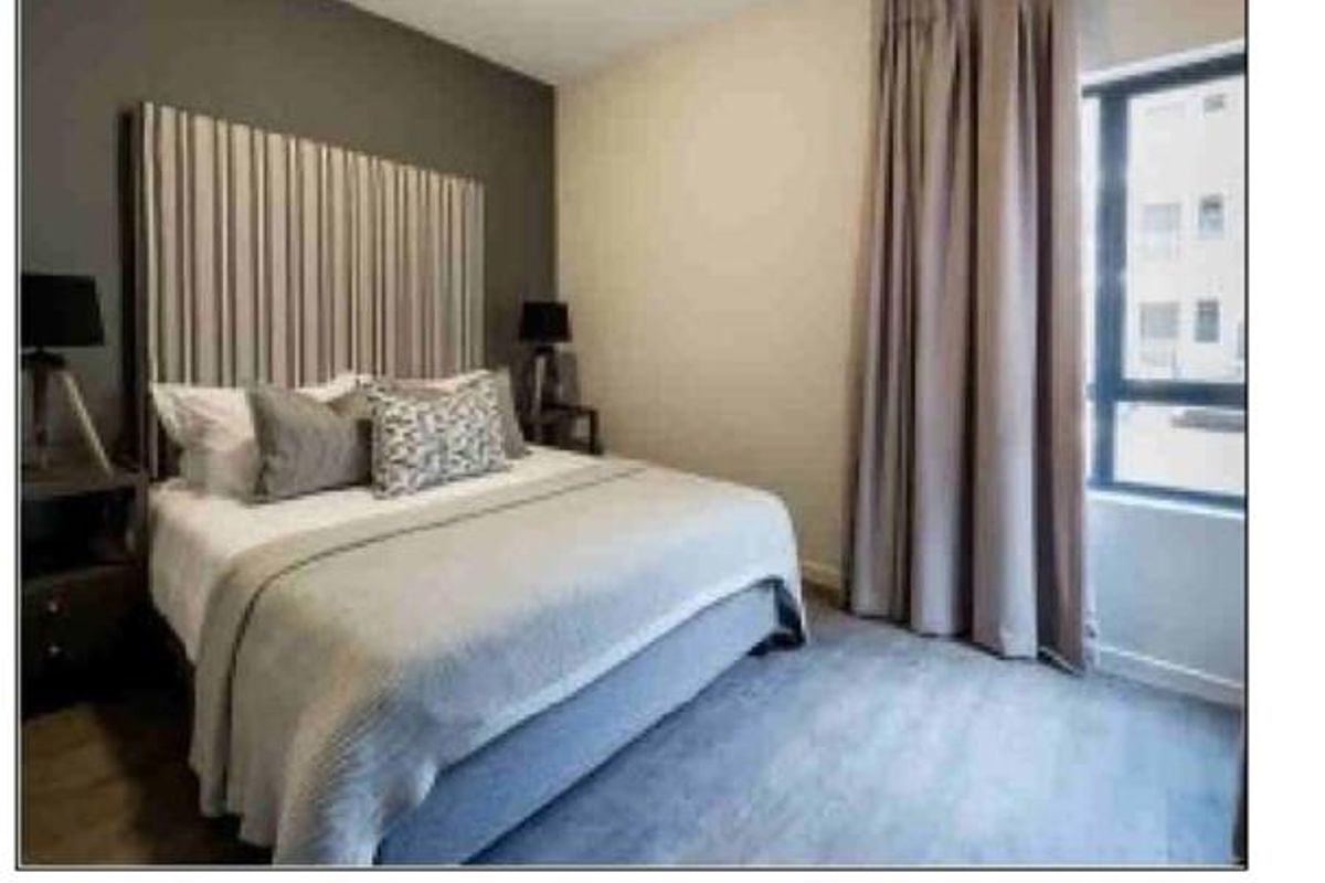 A bedroom featuring a dark accent wall and window with curtain tracks.