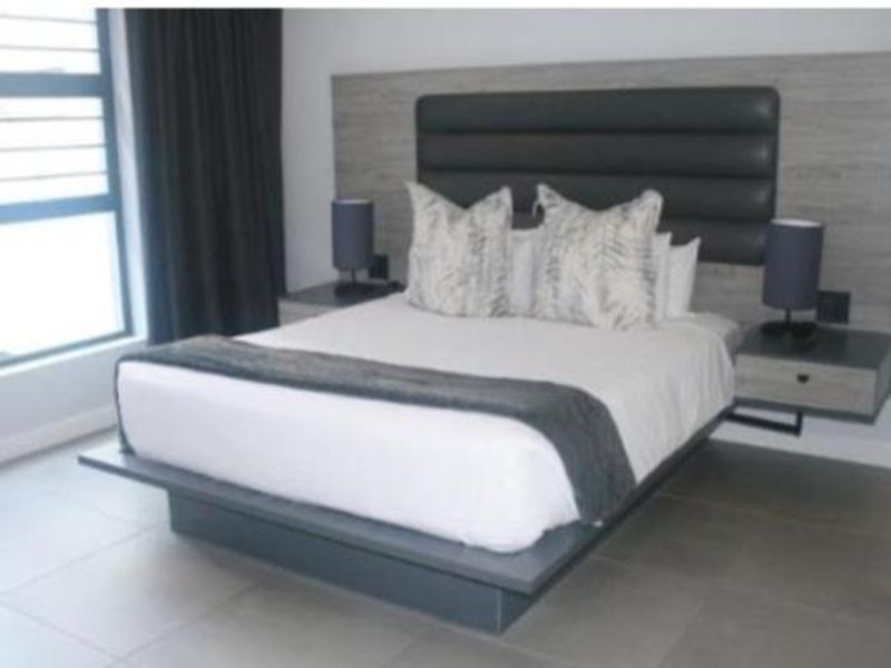 A modern bedroom featuring a built-in headboard, floating bedside tables, and large-format floor tiles with a contemporary aesthetic.