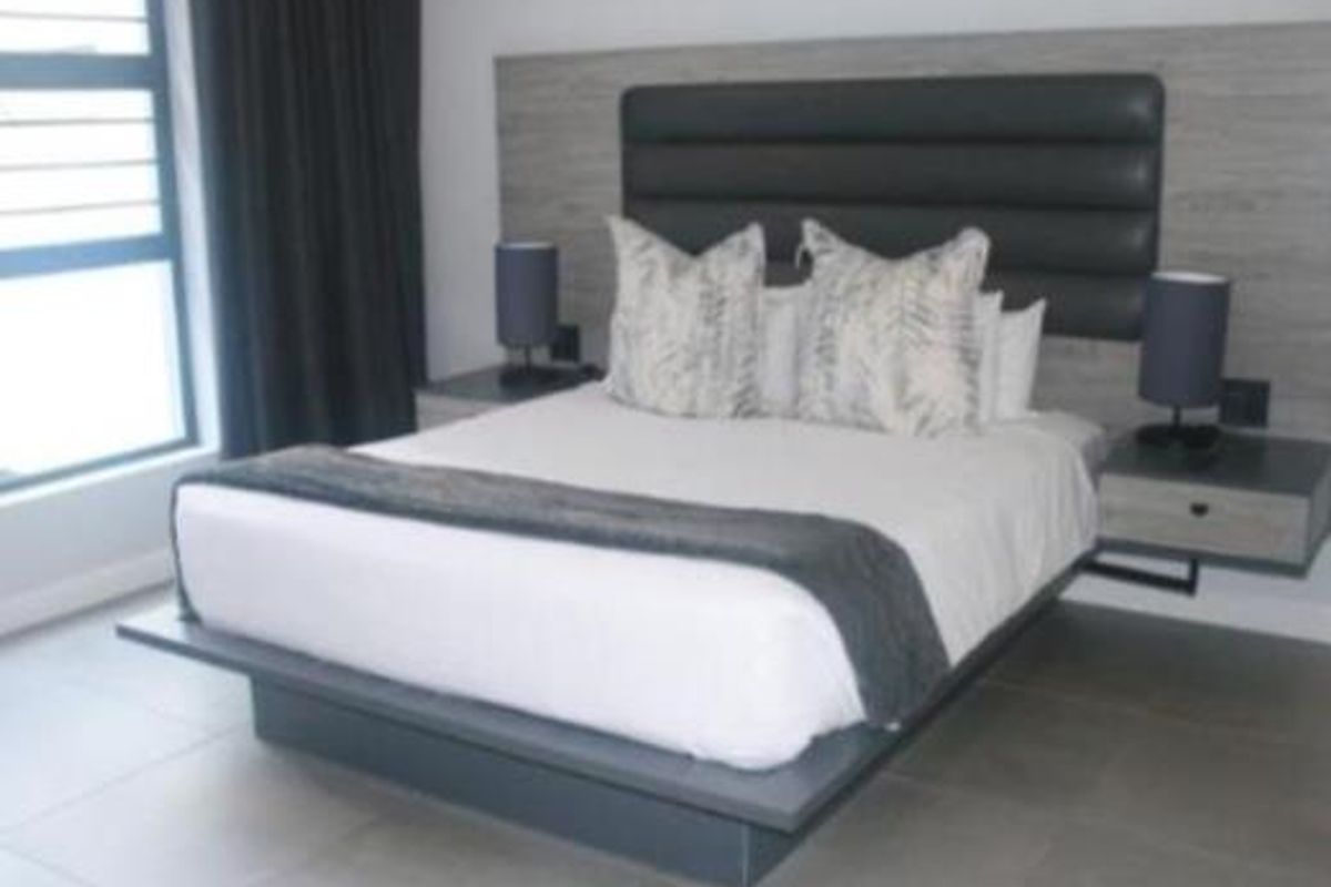 A modern bedroom featuring a built-in headboard, floating bedside tables, and large-format floor tiles with a contemporary aesthetic.