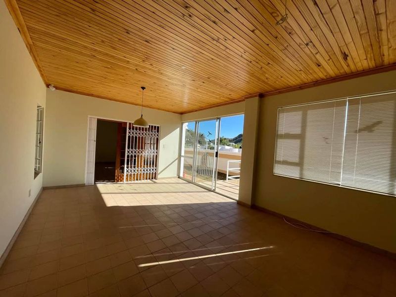 Spacious enclosed patio featuring a warm timber ceiling, tiled flooring, and large sliding glass doors that provide ample natural light and outdoor access.