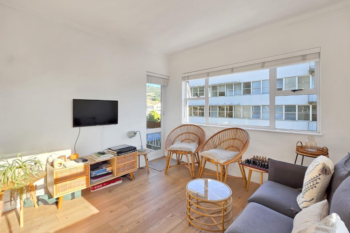 Bright living room featuring large windows, laminate flooring, and direct access to a small balcony.